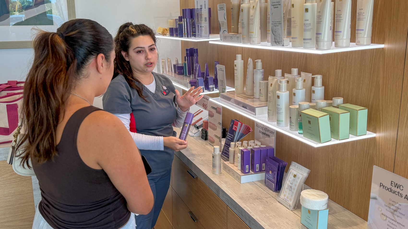 Ruby walking a guest through aftercare products at the retail wall